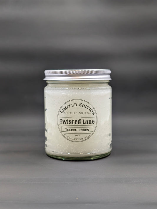 A clear jar with a silver screw top lid with a black label that says Twisted Lane Candles and Tuleul Linden.